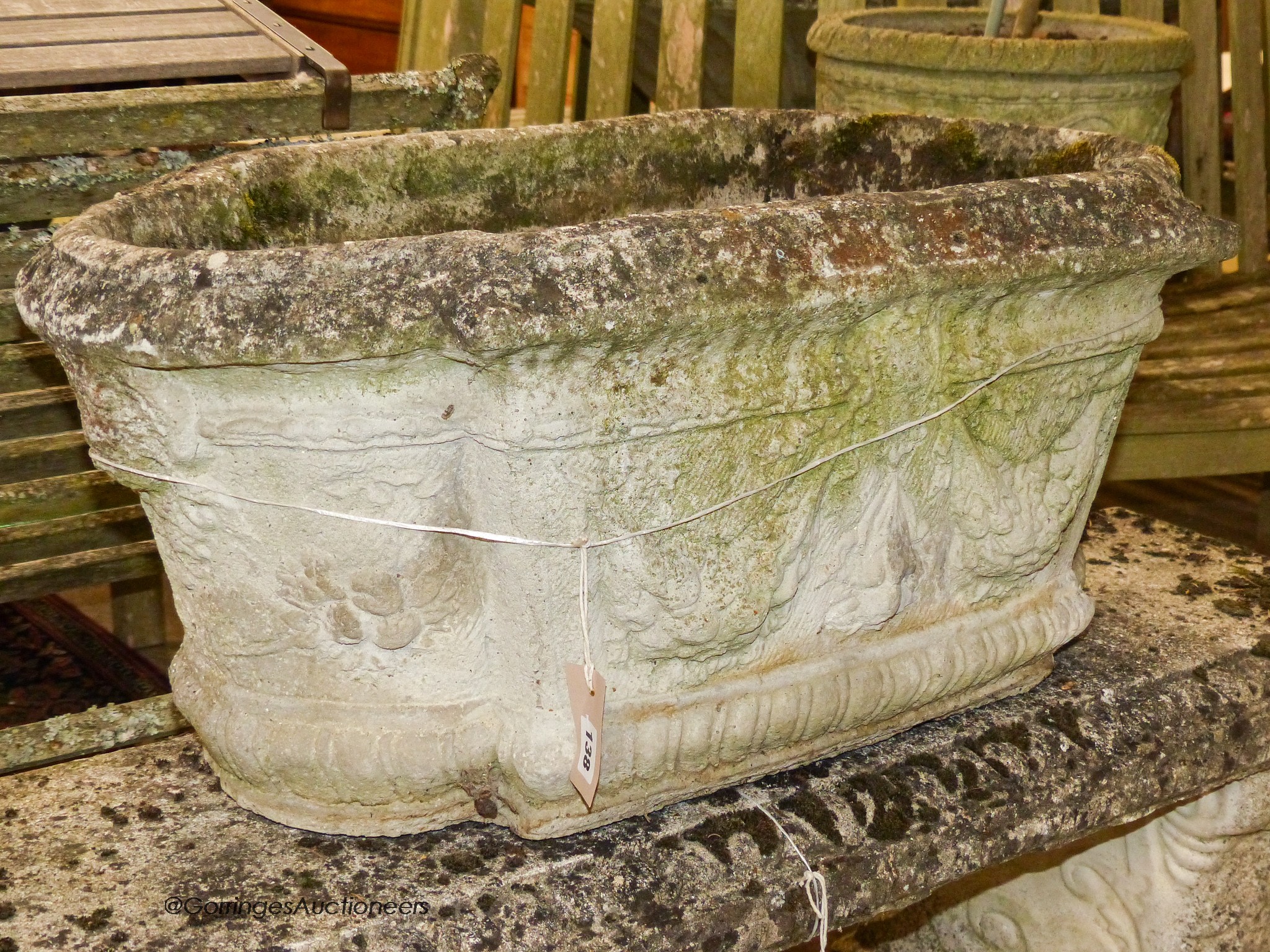 A pair of reconstituted stone shaped oval planters with swag decoration, width 80cm, height 42cm